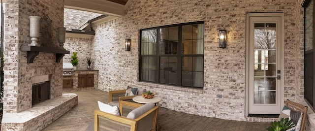 exterior space featuring an outdoor brick fireplace, wood-type flooring, and brick wall