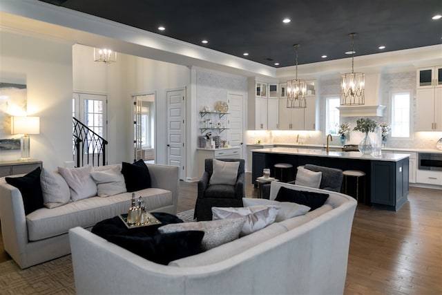 living room featuring crown molding, dark wood-type flooring, a notable chandelier, and sink