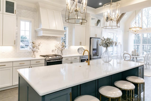 kitchen with a center island with sink, stainless steel appliances, an inviting chandelier, and pendant lighting