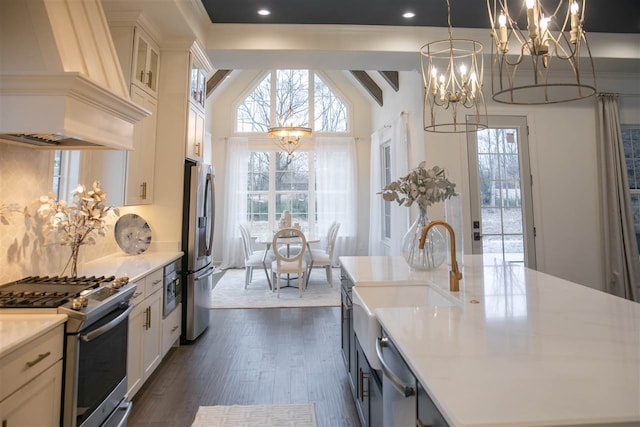 kitchen with white cabinetry, a kitchen island with sink, stainless steel appliances, a notable chandelier, and custom exhaust hood