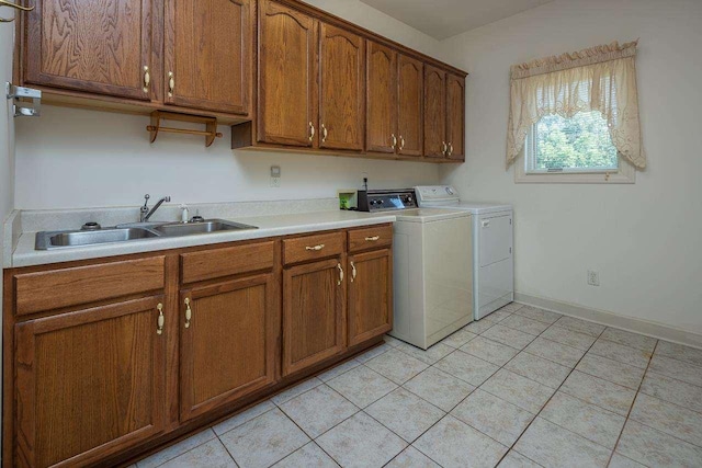 clothes washing area with sink, light tile floors, cabinets, and washer and clothes dryer