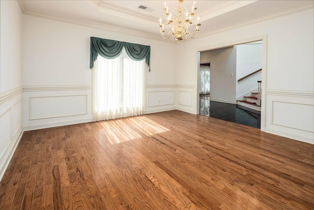 spare room featuring crown molding, a chandelier, a tray ceiling, and dark hardwood / wood-style flooring