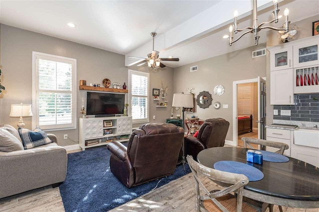 living room featuring ceiling fan with notable chandelier, beam ceiling, and light hardwood / wood-style floors