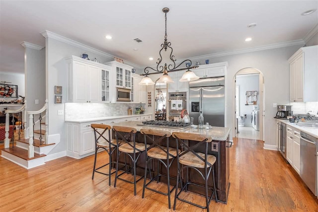 kitchen featuring tasteful backsplash, stainless steel appliances, a kitchen island with sink, and white cabinetry