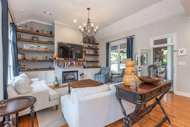 living room featuring ornamental molding, vaulted ceiling, light hardwood / wood-style floors, and an inviting chandelier