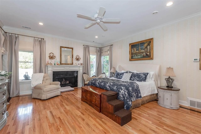 bedroom featuring light hardwood / wood-style flooring, ceiling fan, crown molding, and multiple windows