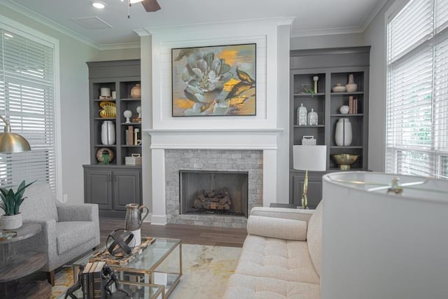 living room with ceiling fan, built in features, dark wood-type flooring, and crown molding