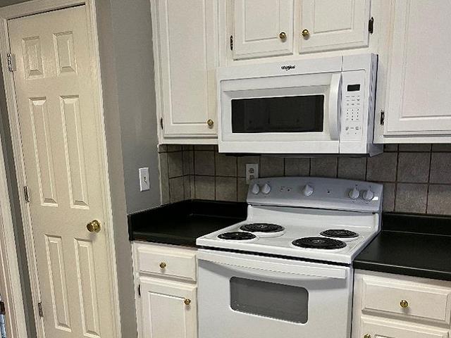 kitchen featuring white appliances, white cabinets, and tasteful backsplash