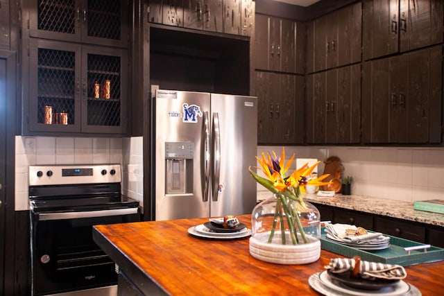 kitchen featuring backsplash, light stone countertops, stainless steel appliances, and dark brown cabinetry