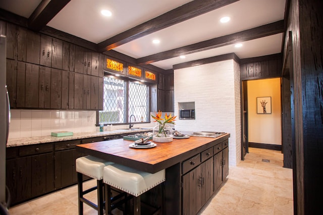 kitchen featuring sink, beamed ceiling, dark brown cabinetry, and light tile floors