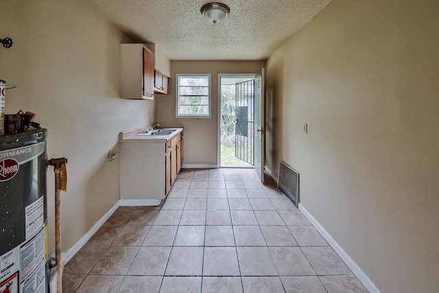 kitchen featuring sink, gas water heater, light tile floors, and a textured ceiling