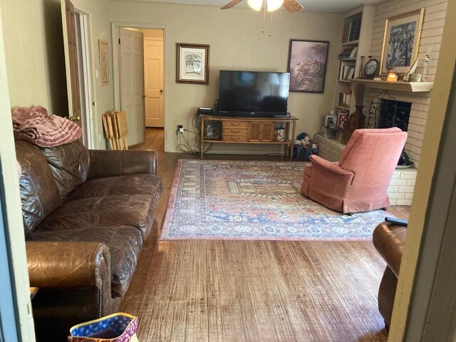 living room featuring brick wall, ceiling fan, hardwood / wood-style flooring, and a fireplace