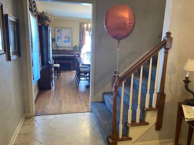 staircase with an inviting chandelier, light tile flooring, and ornamental molding