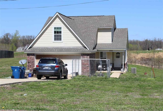 view of front facade featuring a front yard, a garage, and central air condition unit