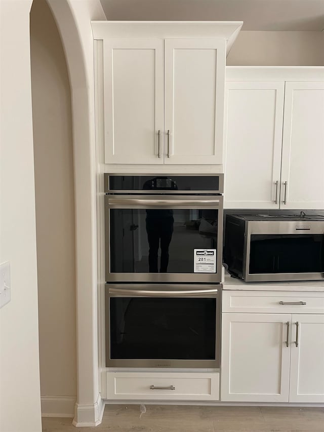 kitchen featuring double oven, light hardwood / wood-style floors, and white cabinetry