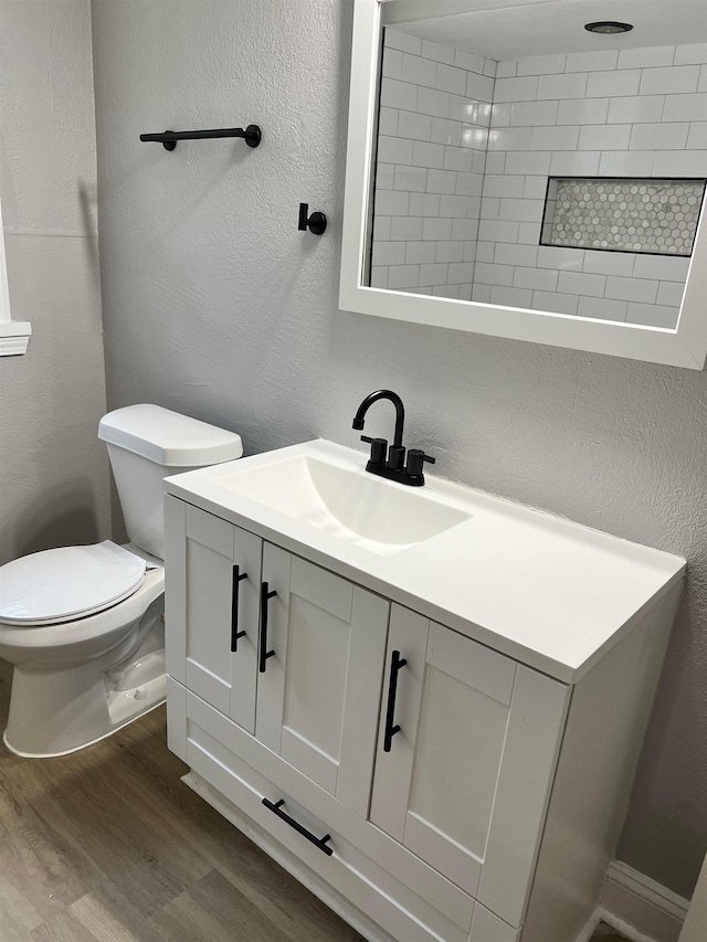 bathroom featuring toilet, wood-type flooring, and vanity