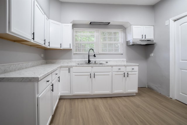 kitchen with white cabinets, light hardwood / wood-style flooring, and sink