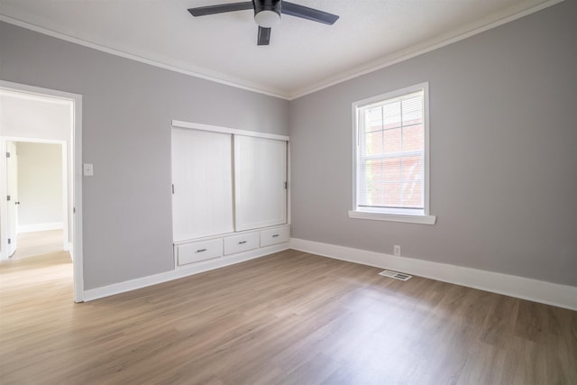 unfurnished bedroom featuring ceiling fan, light hardwood / wood-style flooring, ornamental molding, and a closet