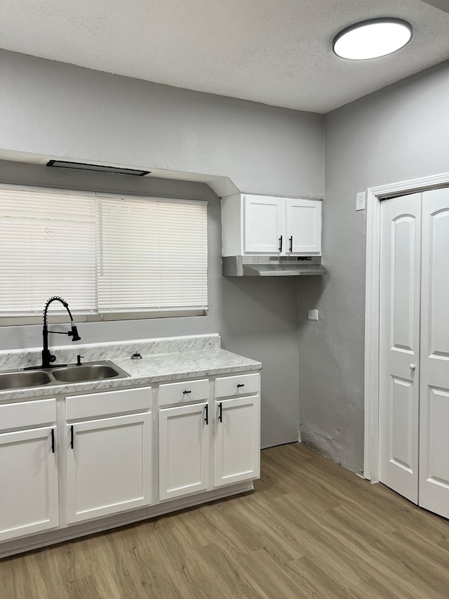 kitchen with sink, white cabinetry, and light wood-type flooring