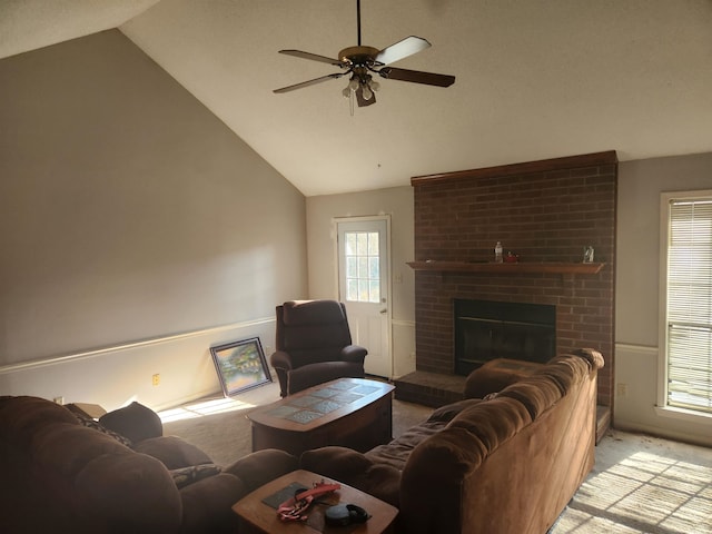 carpeted living room with ceiling fan, brick wall, a brick fireplace, and high vaulted ceiling