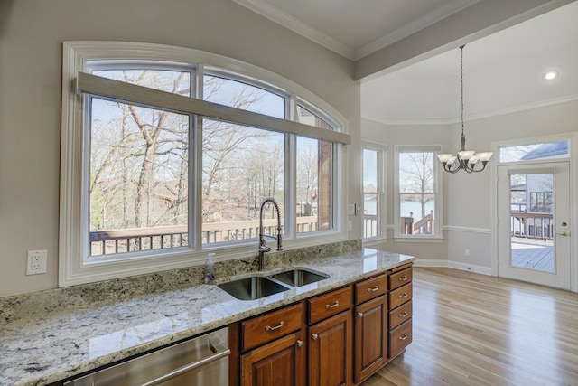 kitchen with a healthy amount of sunlight, hanging light fixtures, light wood-type flooring, and light stone counters