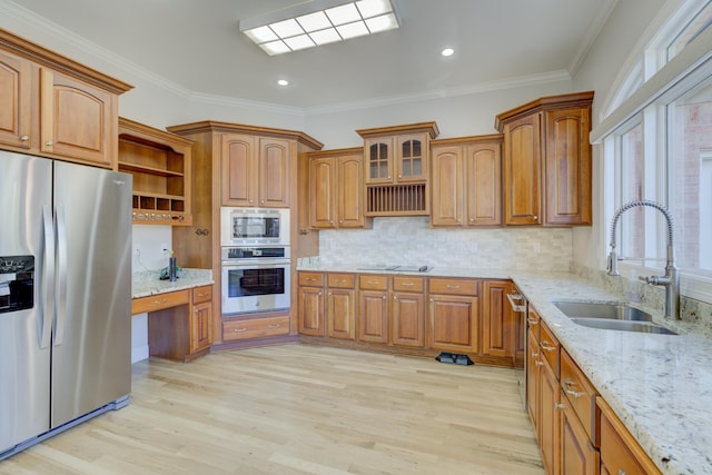 kitchen with sink, light hardwood / wood-style flooring, stainless steel appliances, light stone counters, and crown molding