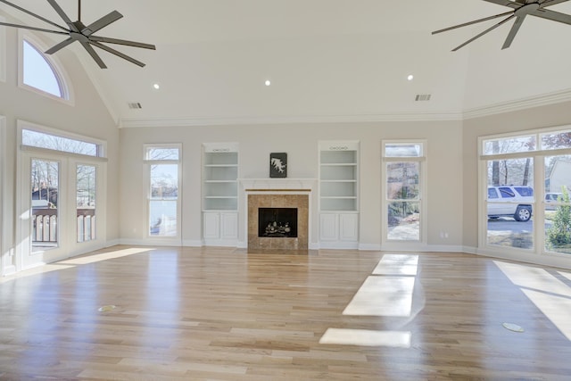 unfurnished living room with ceiling fan, high vaulted ceiling, light hardwood / wood-style flooring, built in features, and ornamental molding