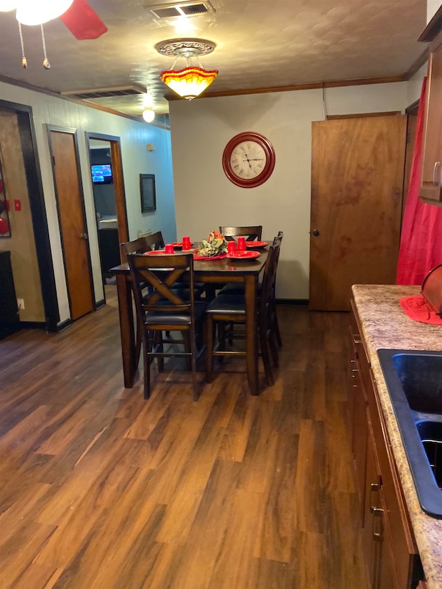 dining space featuring ornamental molding, ceiling fan, sink, and dark hardwood / wood-style flooring