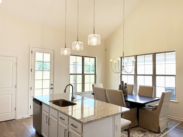 kitchen featuring sink, a center island with sink, dishwasher, light stone countertops, and light hardwood / wood-style floors