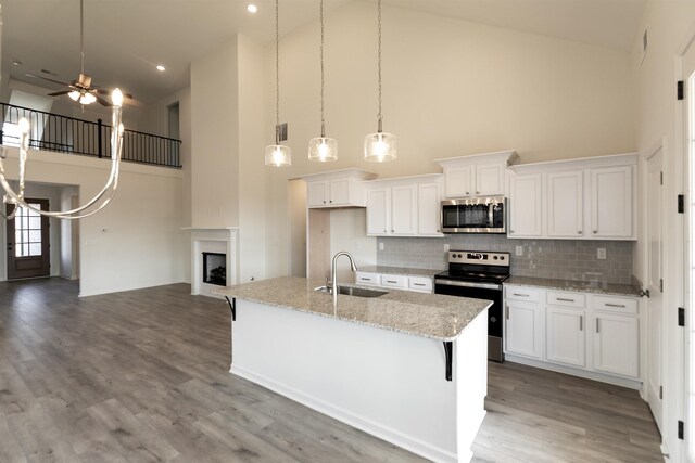 kitchen with decorative light fixtures, sink, white cabinets, a kitchen island with sink, and stainless steel appliances