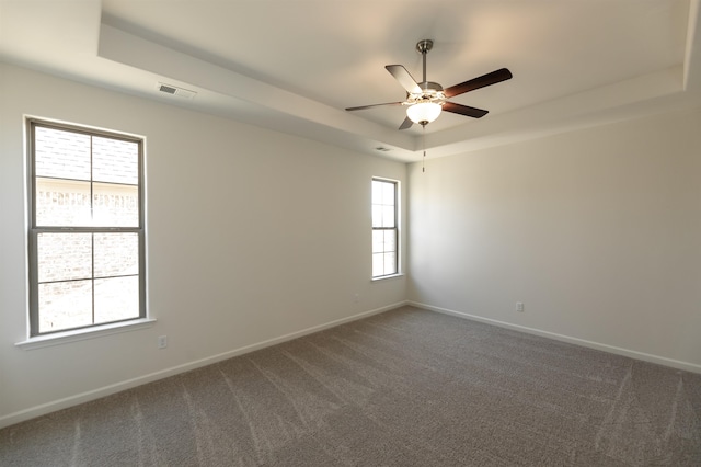 carpeted empty room featuring a raised ceiling and ceiling fan