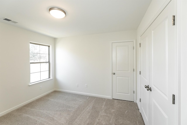 unfurnished bedroom featuring light colored carpet and a closet