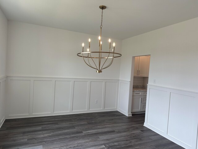 unfurnished dining area with an inviting chandelier and dark wood-type flooring