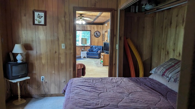 carpeted bedroom with wooden walls, ceiling fan, and a closet