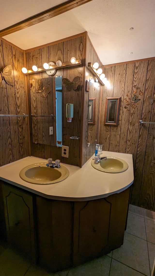 bathroom with dual sinks, wood walls, large vanity, and tile flooring