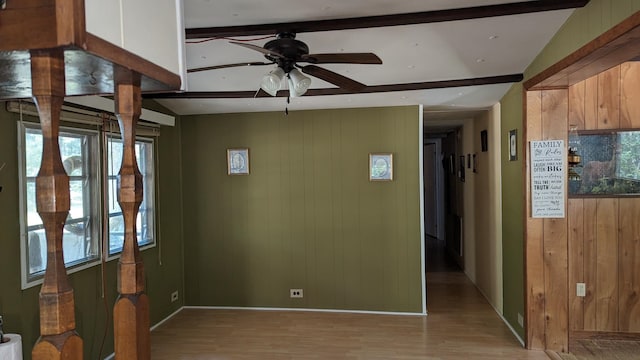 spare room featuring plenty of natural light, light hardwood / wood-style floors, ceiling fan, and beamed ceiling