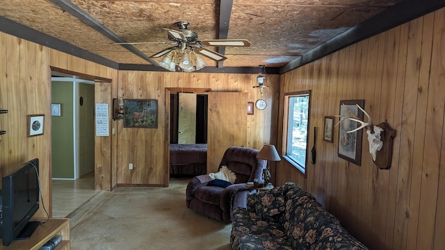 carpeted living room featuring ceiling fan and wood walls