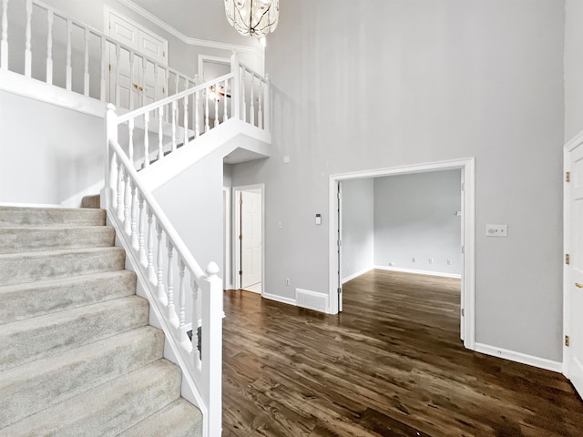 stairway featuring a high ceiling, a notable chandelier, and dark hardwood / wood-style floors