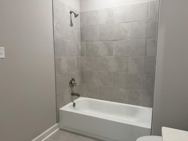 bathroom with tile patterned flooring, toilet, and tiled shower / bath