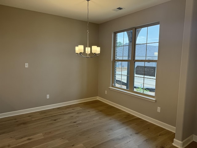 spare room with hardwood / wood-style flooring and an inviting chandelier