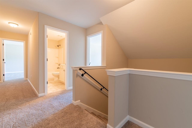 hall with light carpet and vaulted ceiling