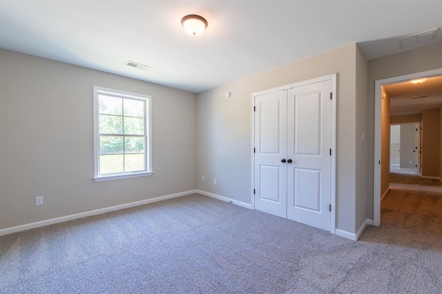 unfurnished bedroom featuring a closet and light colored carpet