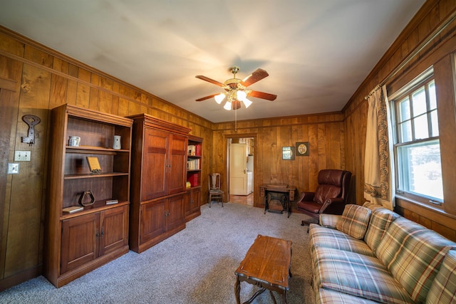 carpeted living room featuring ceiling fan and wooden walls