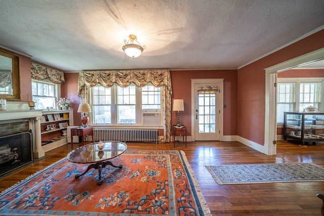 living room with dark hardwood / wood-style floors, a brick fireplace, a wealth of natural light, and radiator heating unit