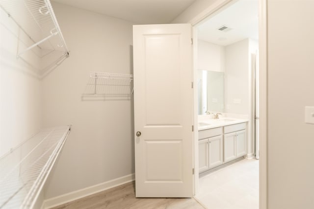 spacious closet featuring sink and light hardwood / wood-style flooring