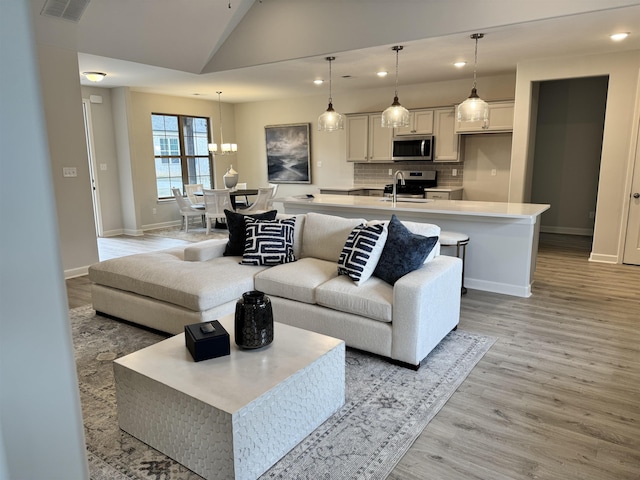 living room featuring lofted ceiling, sink, and light wood-type flooring