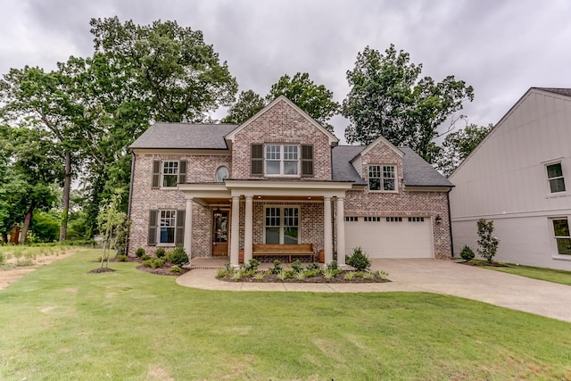 view of front of property featuring a front yard, covered porch, and a garage