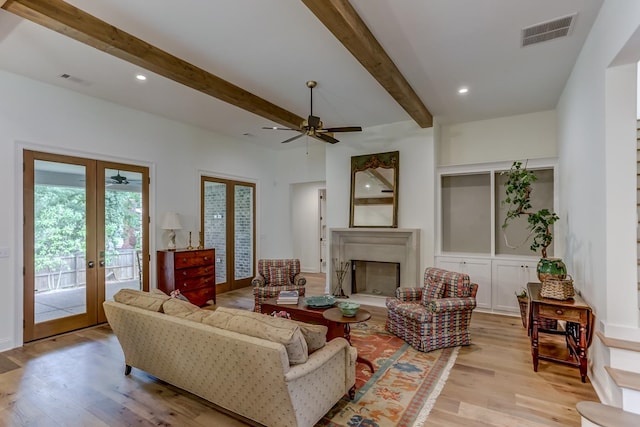 living room featuring light hardwood / wood-style floors, ceiling fan, french doors, and beamed ceiling