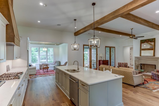 kitchen with light hardwood / wood-style flooring, a kitchen island with sink, decorative light fixtures, and sink