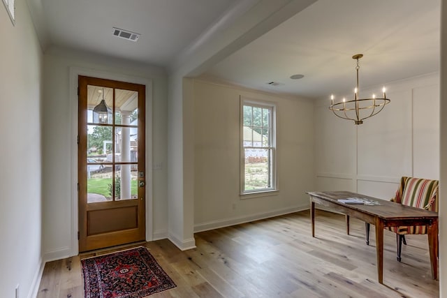 doorway to outside featuring a notable chandelier and light hardwood / wood-style flooring